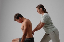 Picture of client sitting on table receiving treatment on his back